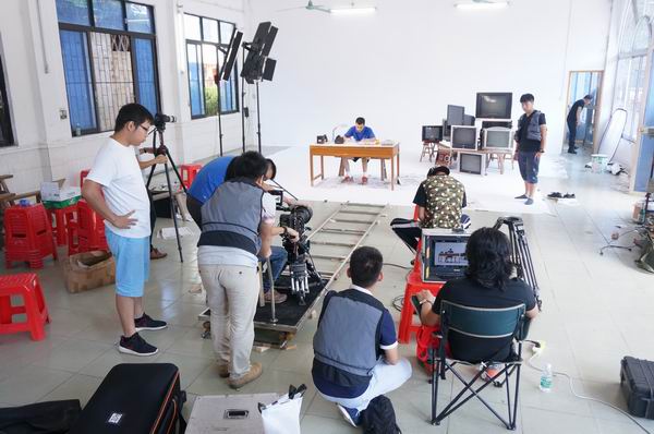 图为摄影组在拍摄肢残人房思学修理电器的场景