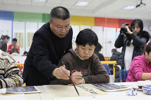 图为文艺志愿者辅导残疾人书法
