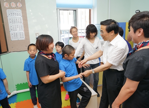 图为程凯副理事长与残疾儿童互动游戏