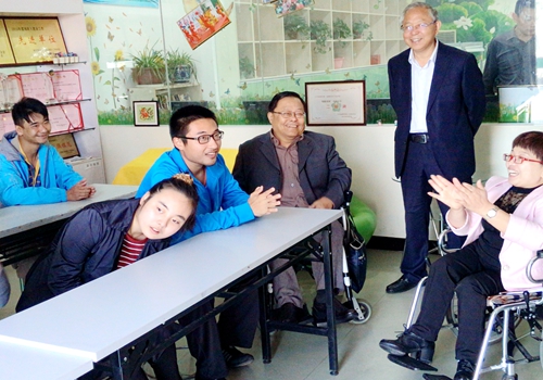图为吕世明在太阳花互助乐园与残疾人及老师亲切交谈