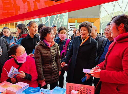 图为张义珍在昆明市西山区人社局开展的“就业援助月”活动现场，与工作人员、援助对象亲切交流，询问援助流程和援助政策落实情况。